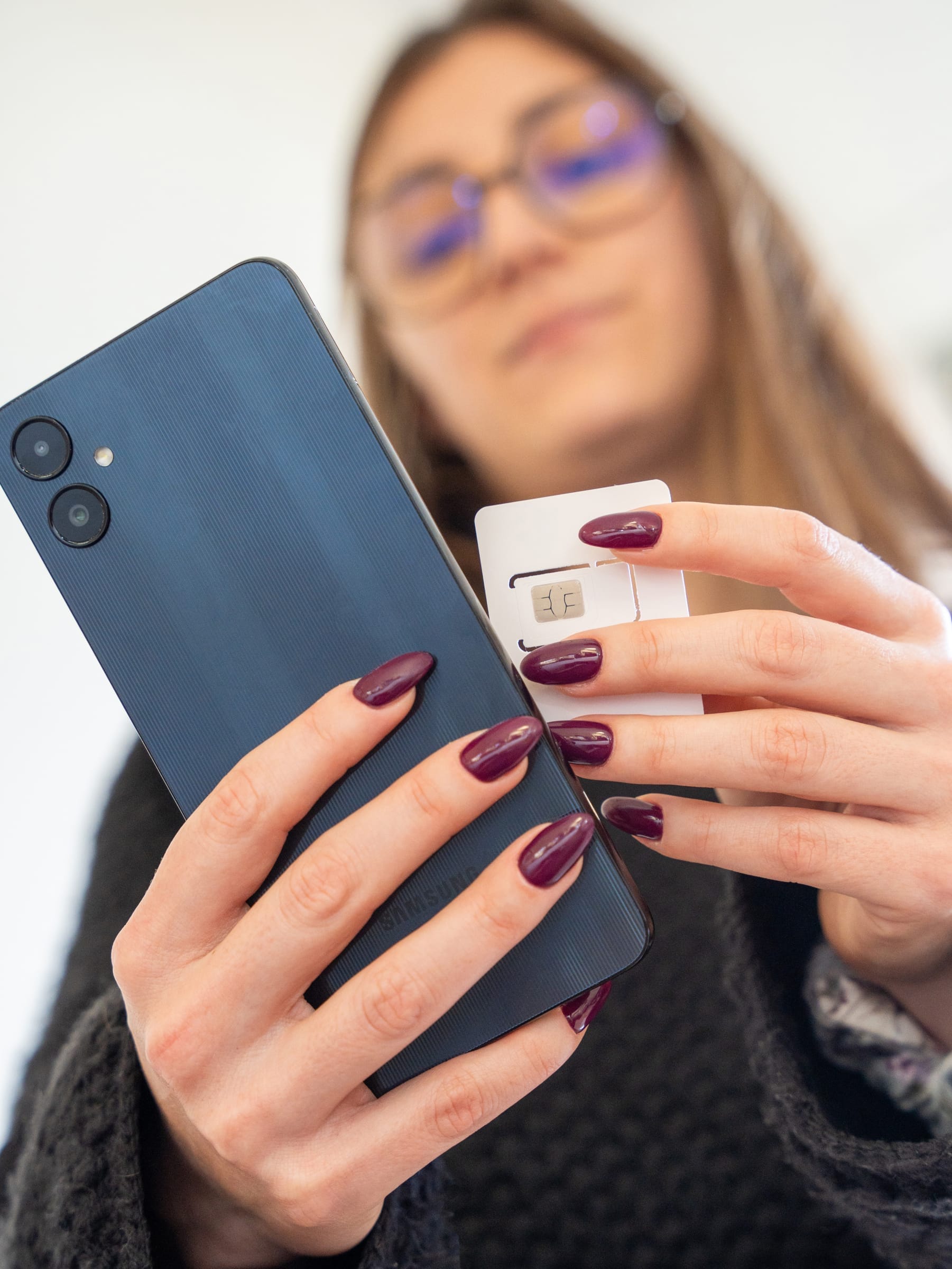Utilisatrice tenant son smartphone et sa carte SIM
